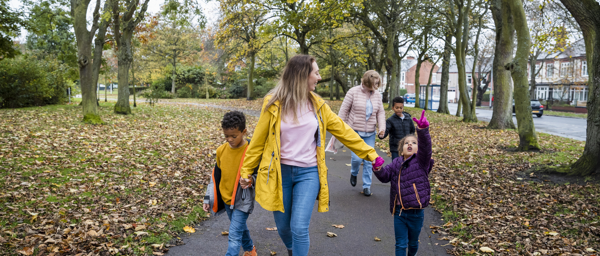 Front-view shot of a multi-gen family walking along a footpath in a public park