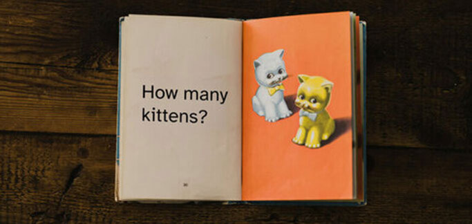 Vintage children's book with "How many kittens?" written on one page and two illustrated kittens on the other.