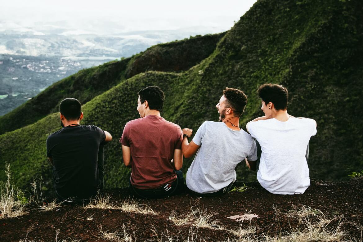 Four men sat on a hillside laughing