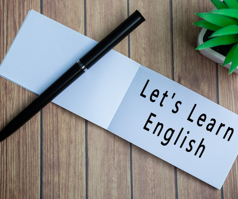A pen and piece of card saying lets learn english
