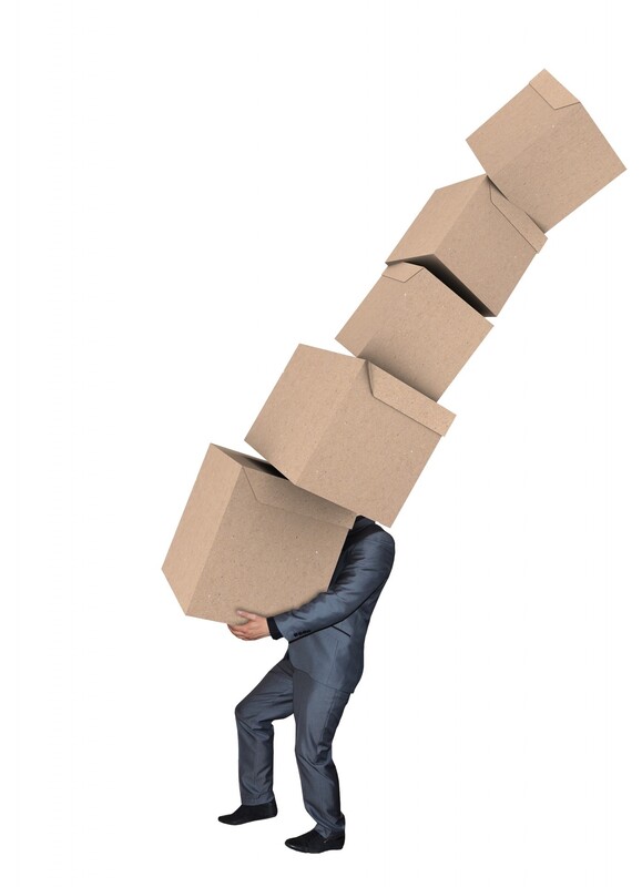 A man struggles to carry several cardboard boxes which are covering his eyes