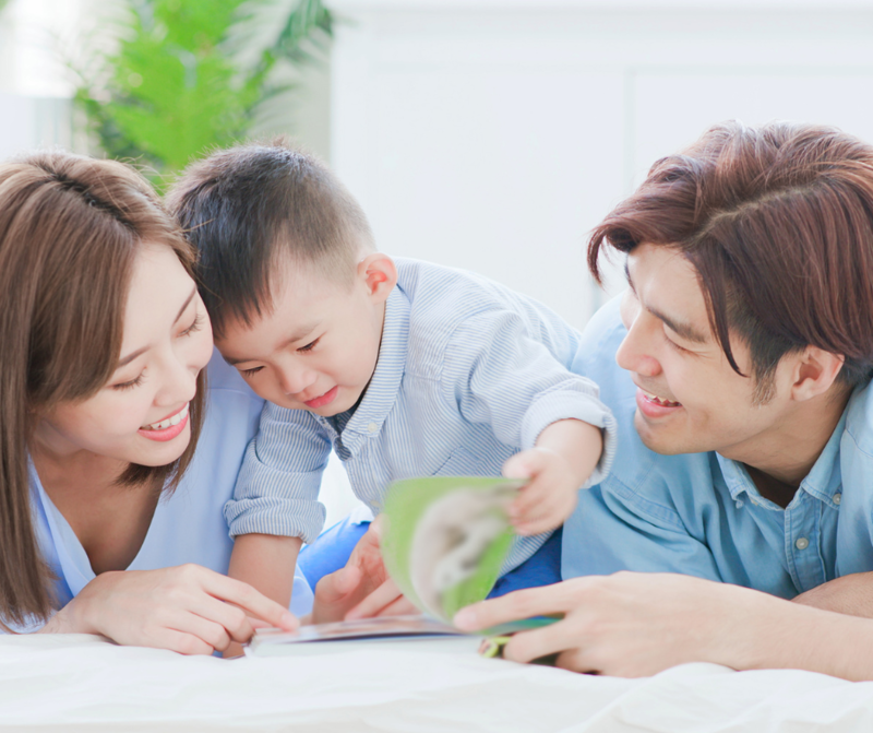 Two parents reading with their child