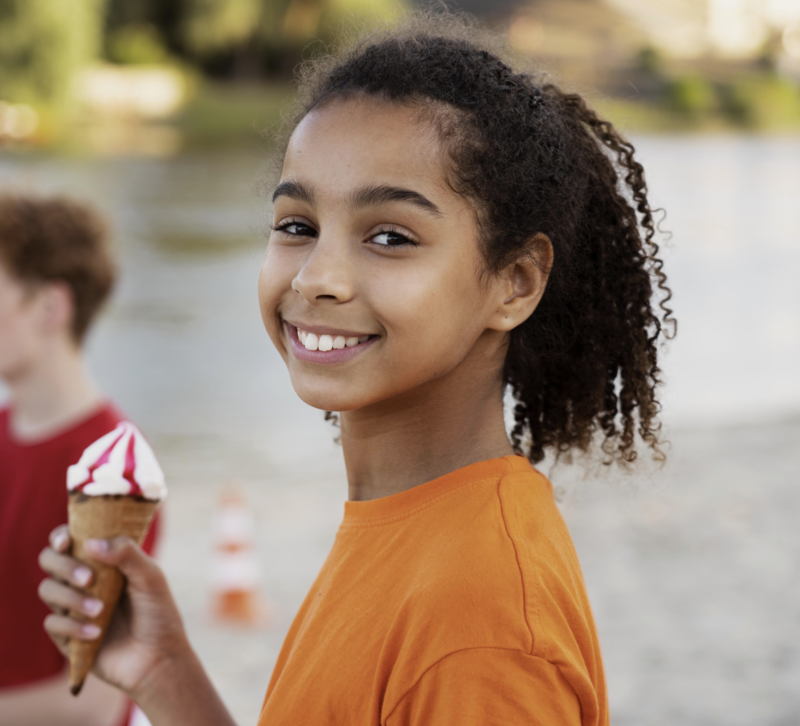 Young girl holding an ice cream smiling at camera