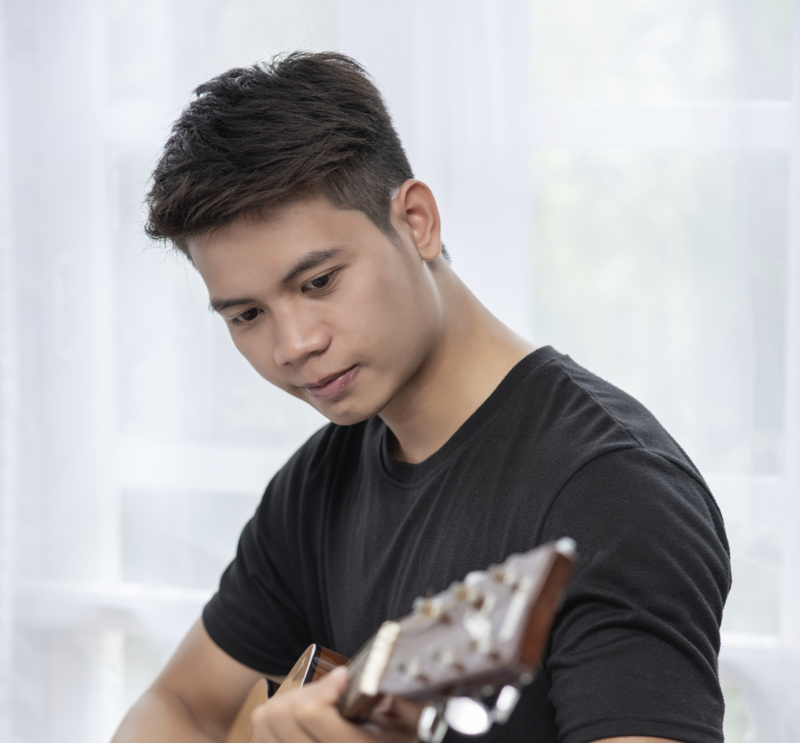 an older teenage boy playing a guitar