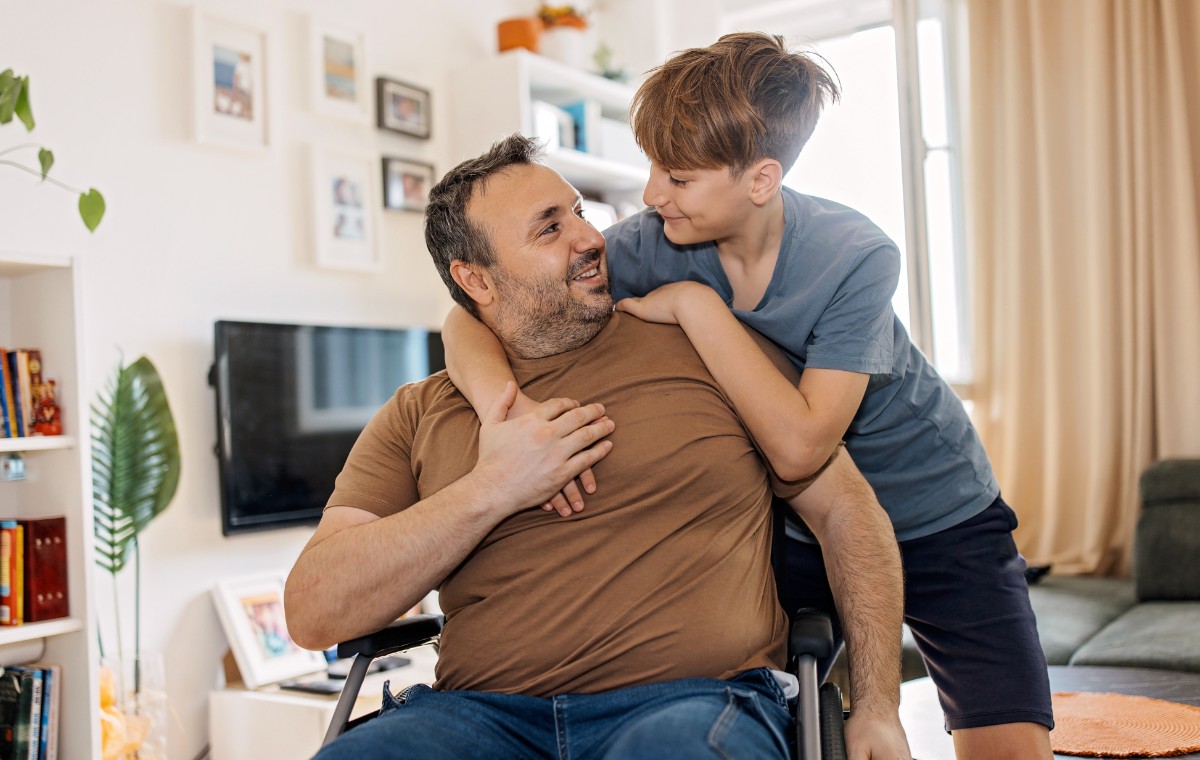 Wheelchair using dad hugged by his son at home